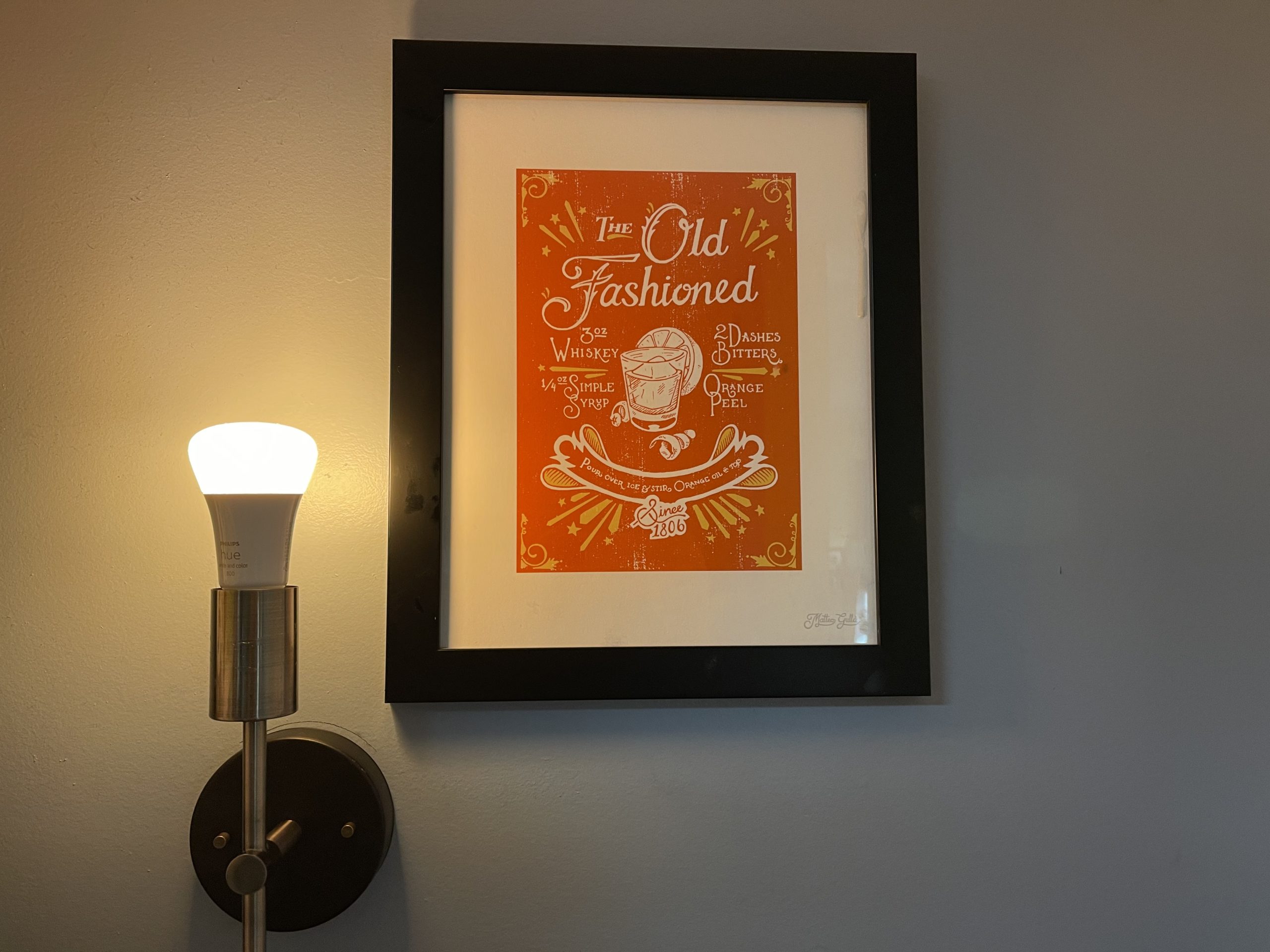 a smart lightbulb on a sconce, next to a picture. 